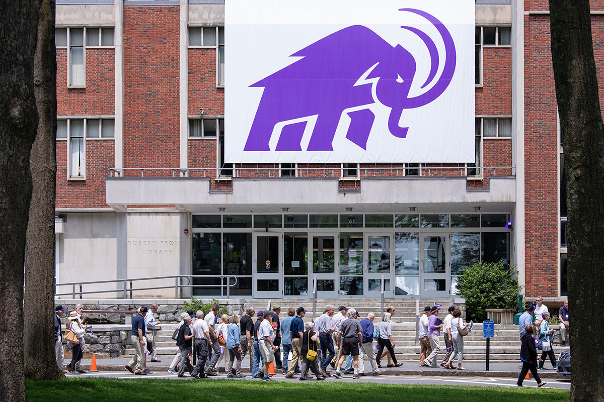 Alumni parading past a large banner of the Mammoth hung on the outside of Frost Library