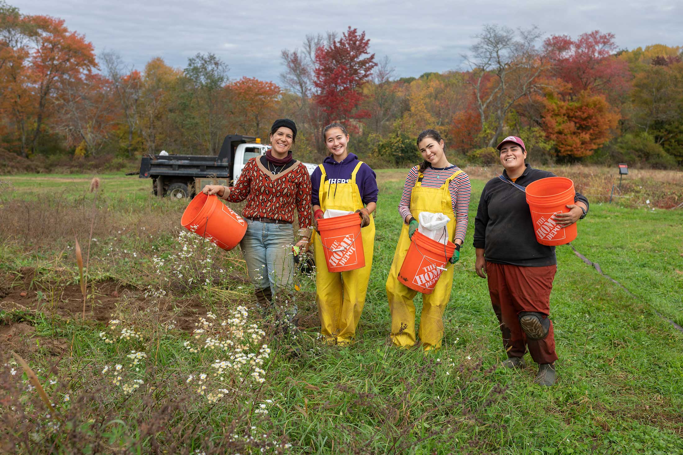 Four women at the Book and Plow Farm pose for a photo by a field.