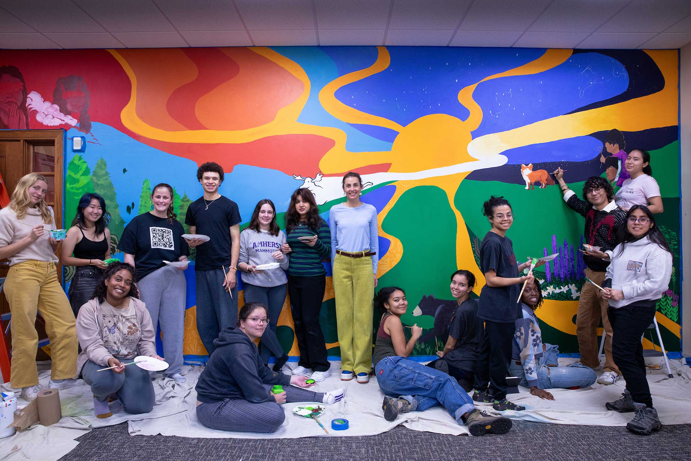 The art class members pose in front of the mural-in-progress.