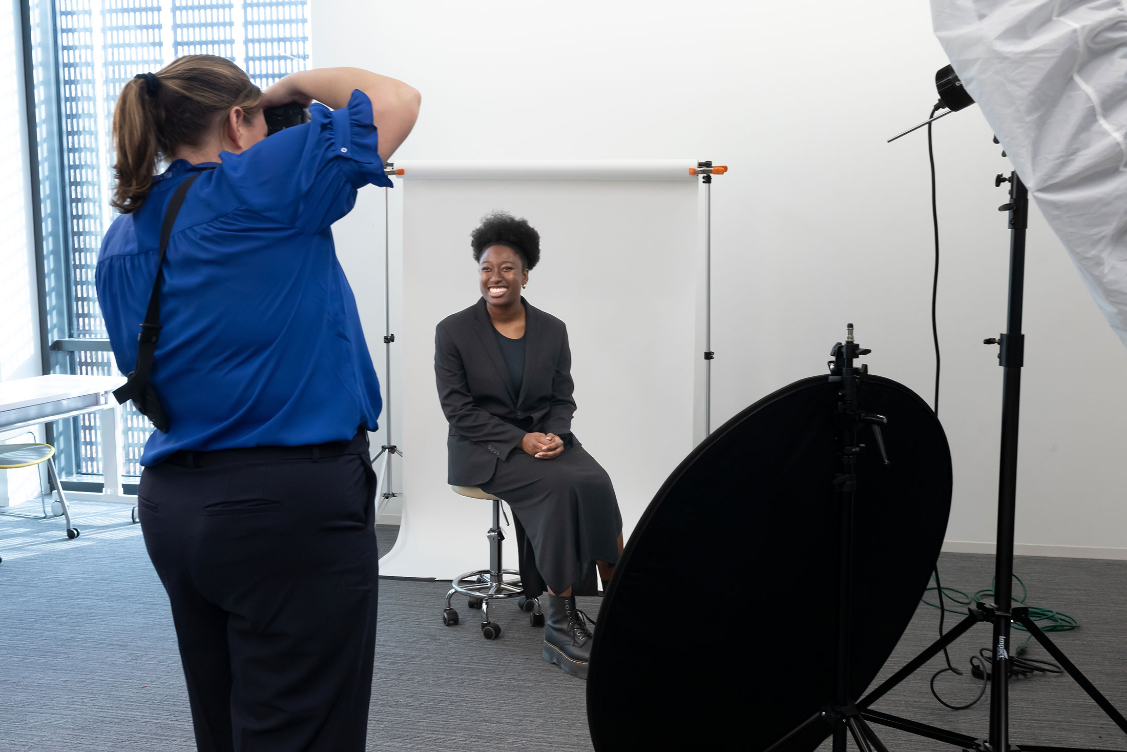 A woman smiles while getting her professional headshot taken.