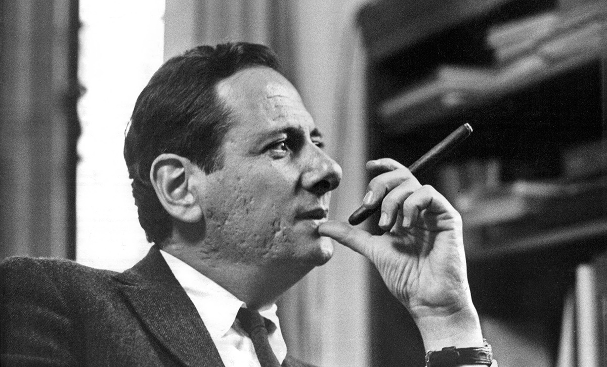 A young man in a suit smoking a cigar