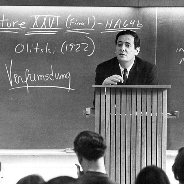 A man standing at a podium in a classroom giving a lecture