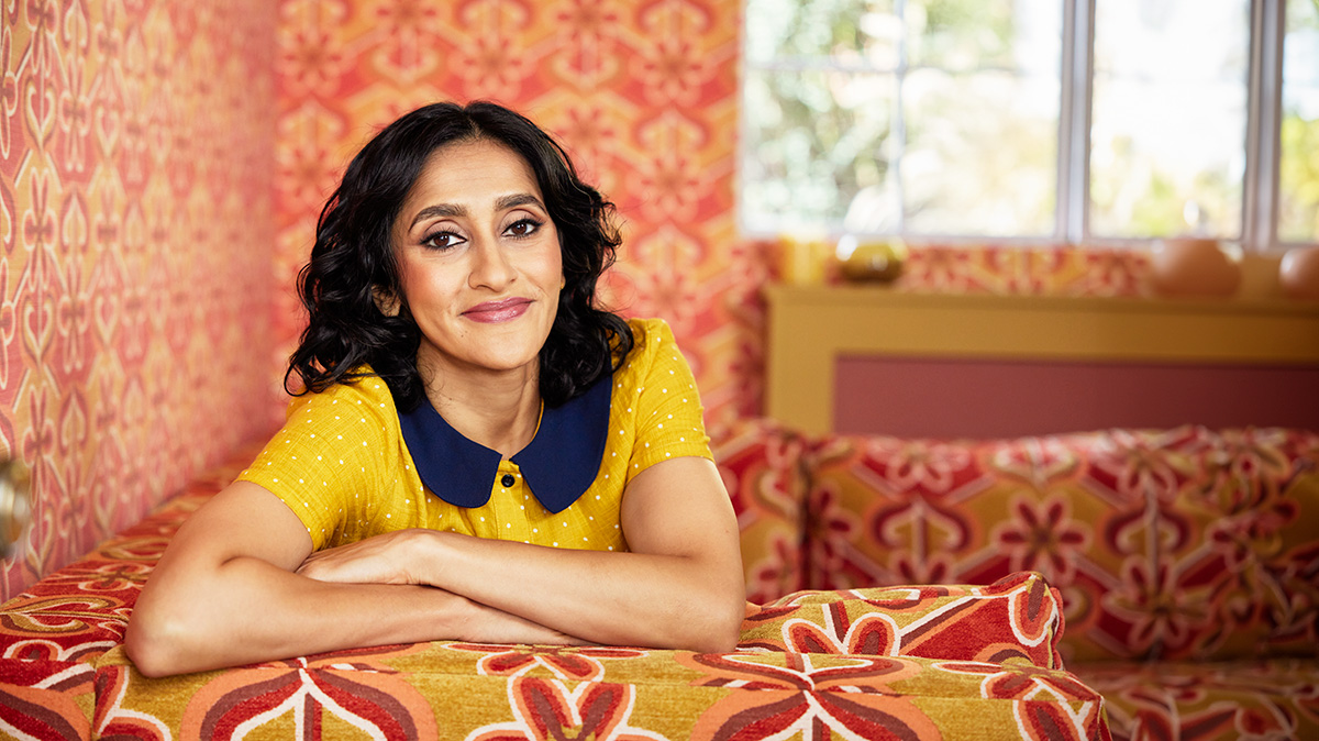 A woman in a yellow shirt sitting on a couch in a colorful room