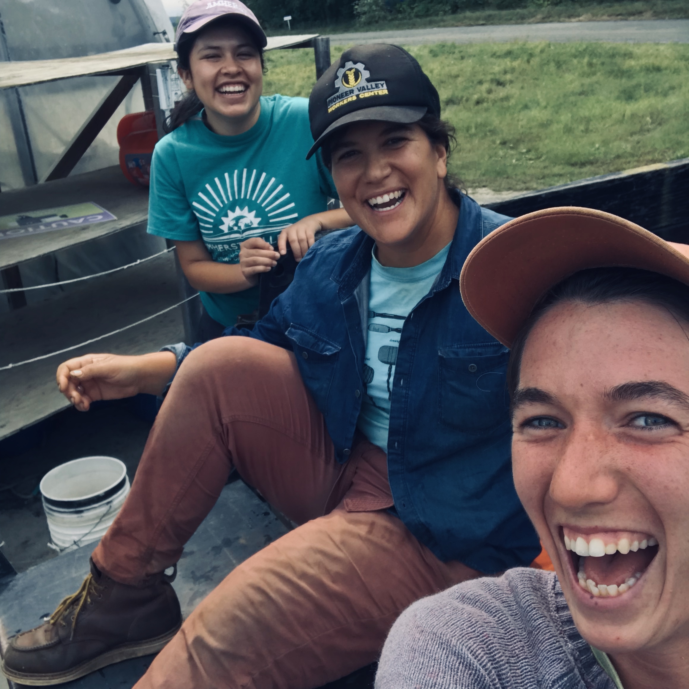 Three woman in the back of a truck smiling and laughing