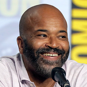 A photo of Jeffrey Wright smiling and speaking at a microphone