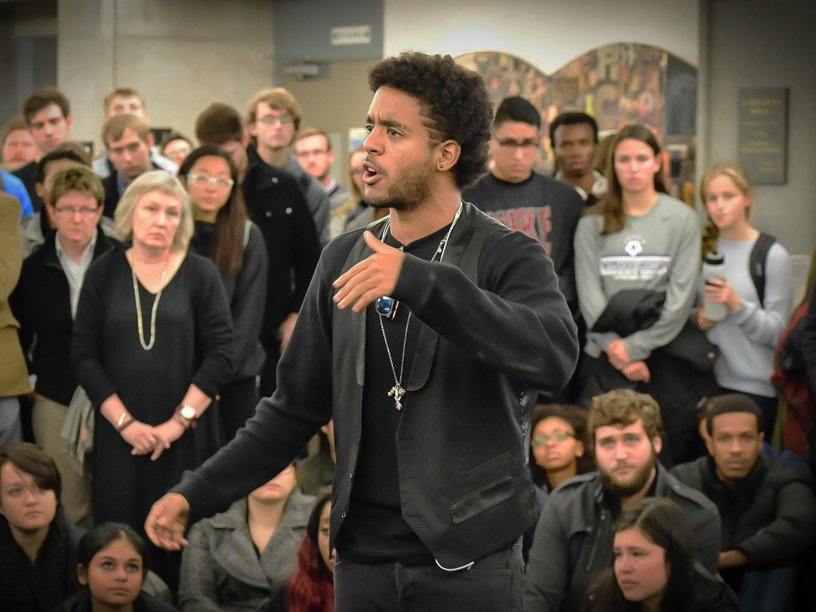 A young Black man speaking in front of a group of people