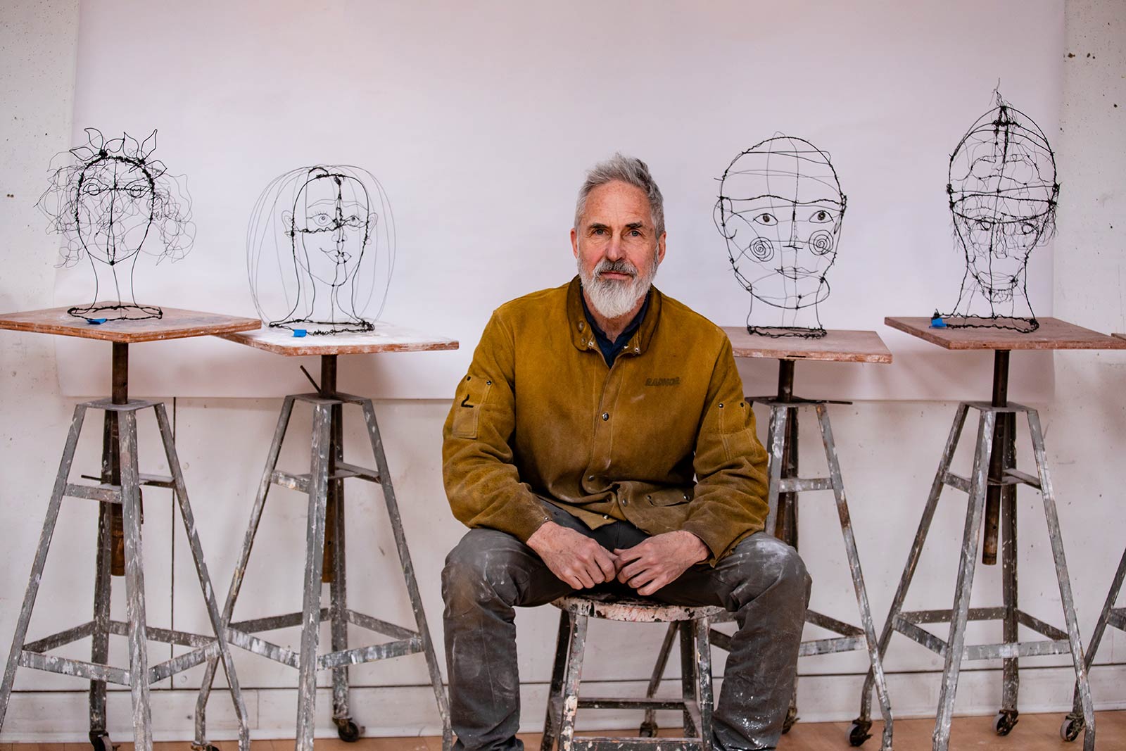 Douglas Culhane, Visiting Lecturer in Art, sitting on a stool, surrounding by student sculpture project