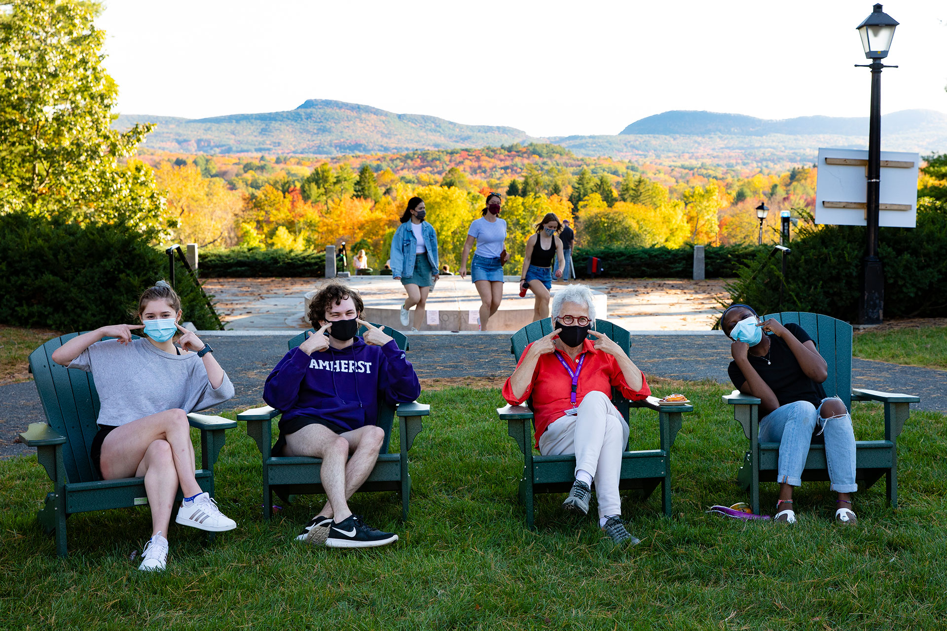 Four people wearing masks sitting on the quad in front of memorial hill