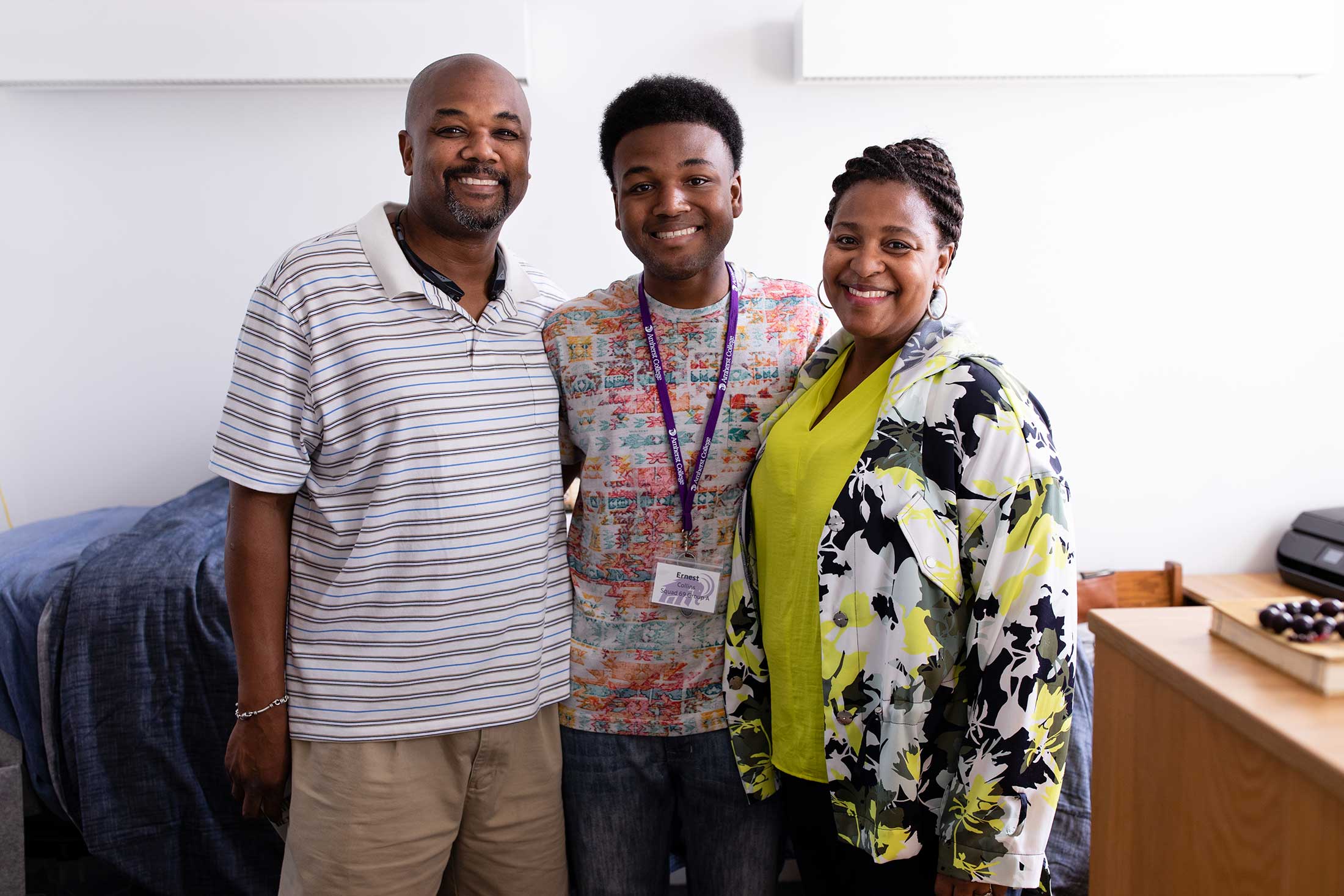 A first year student poses between his mother and father inside his new residence hall.