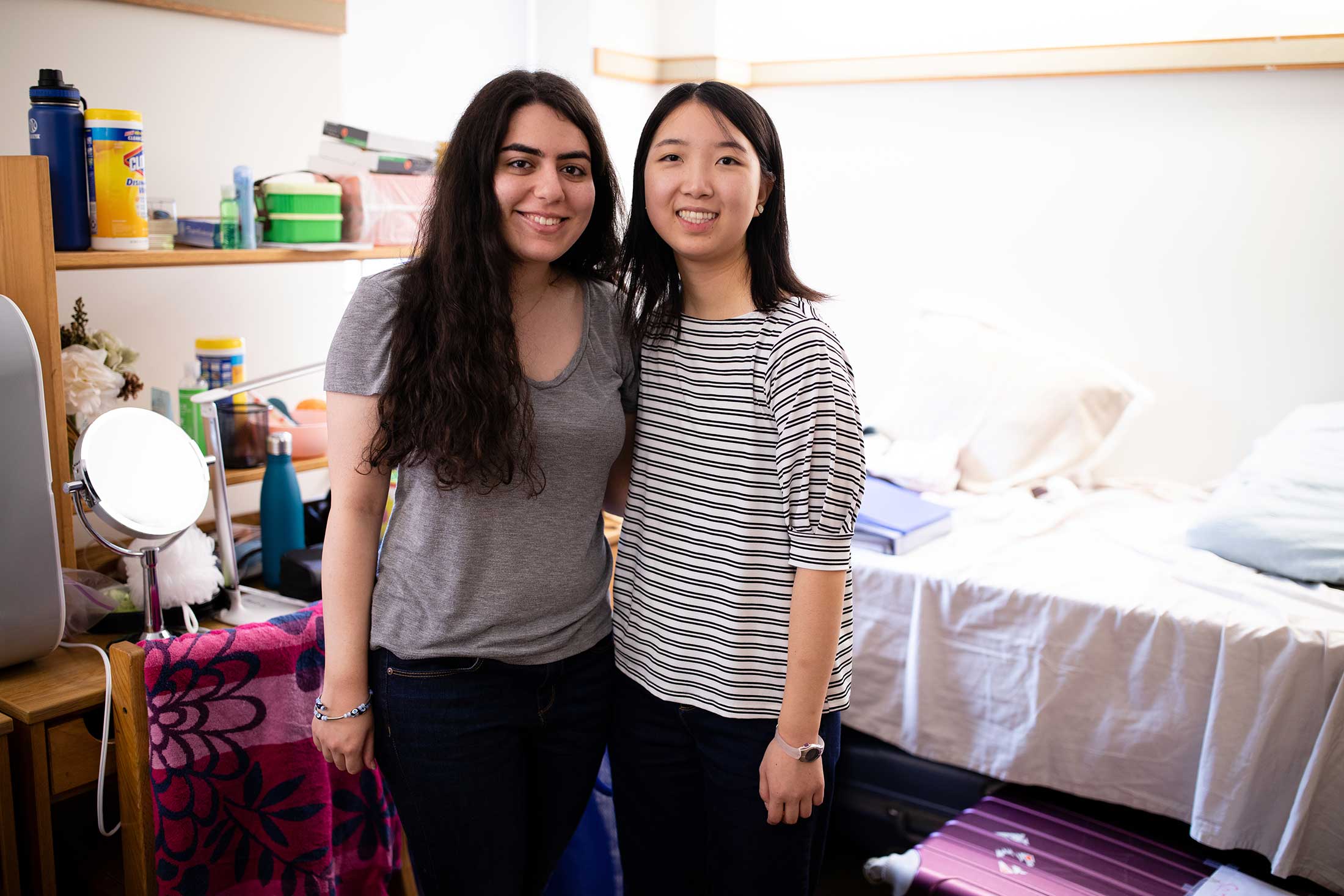 Two new roommates pose for a photo in their shared room