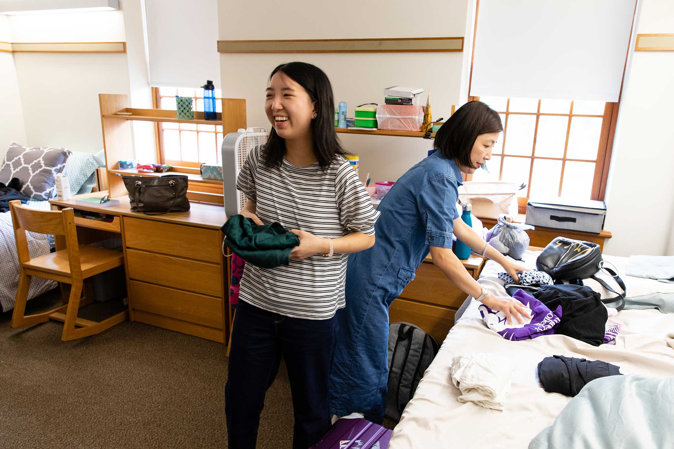 A new student unpacks her belongings in the residence hall with the help of her mother