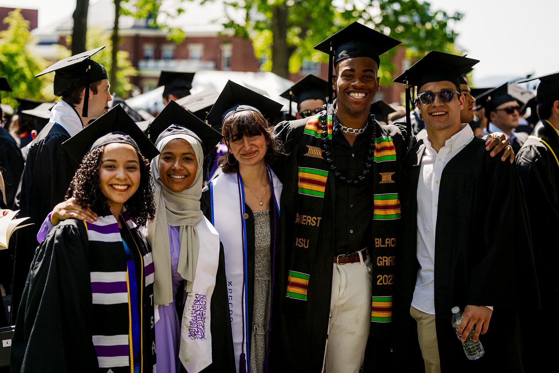 A group of five graduates pose together at the end of the ceremony.
