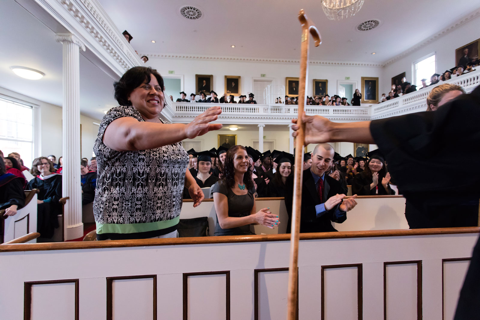 A student in regalia hands an Amherst cane to an honorary class member