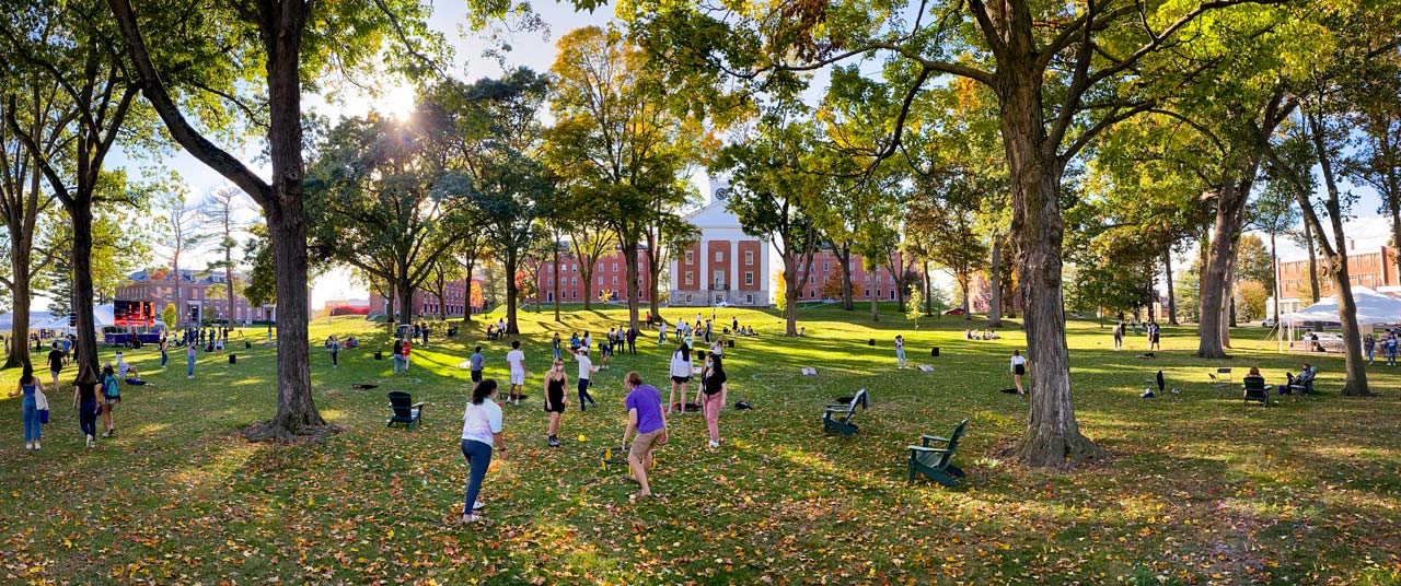 students playing games and relaxing on the quad with sun shining through autumn trees
