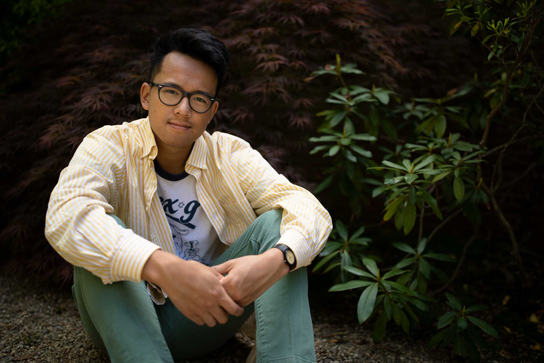 Chris Tun sits outside in the Yushien Japanese Garden on the Amherst College campus.