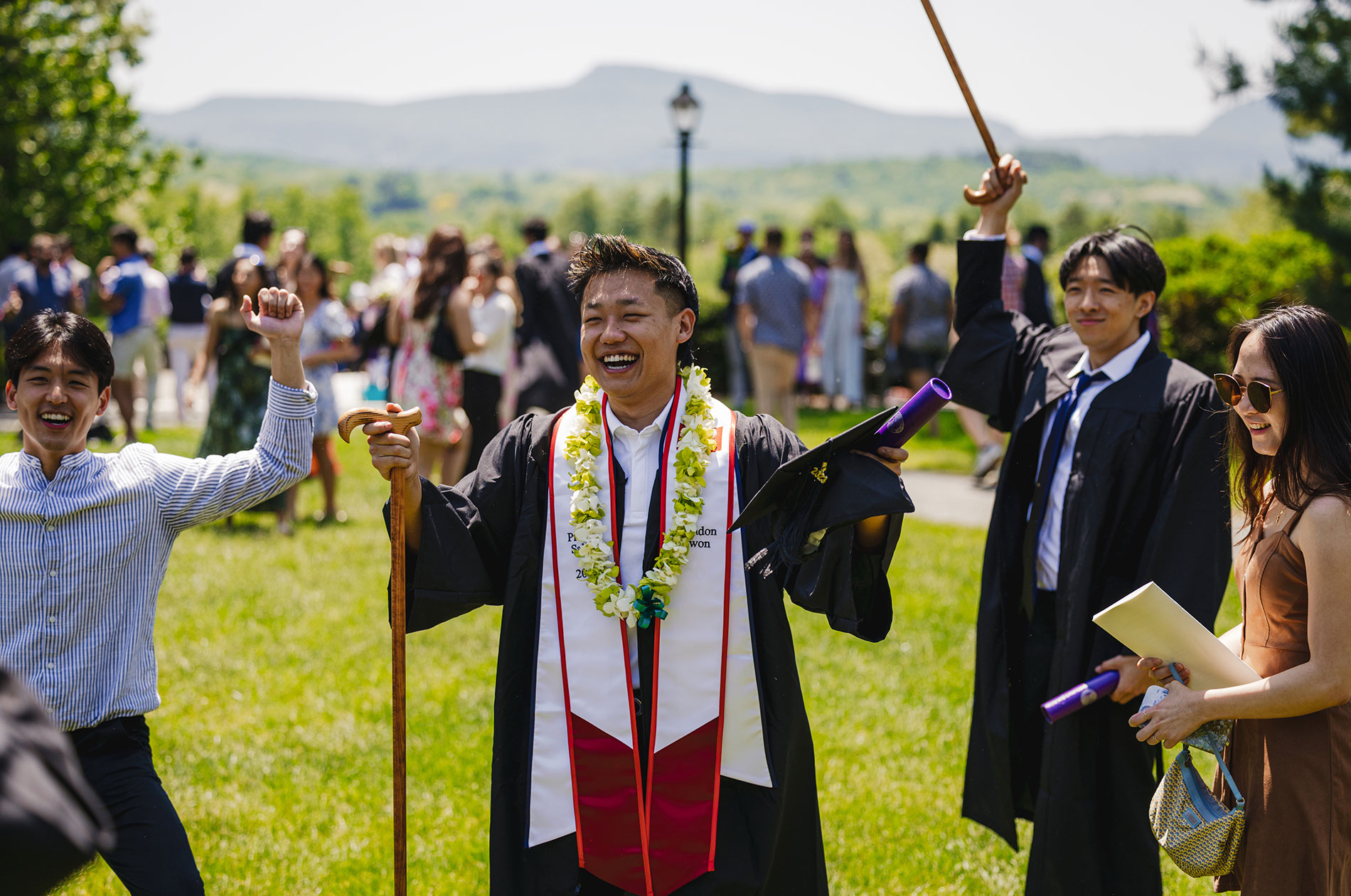 A graduate raises both arms in celebration.