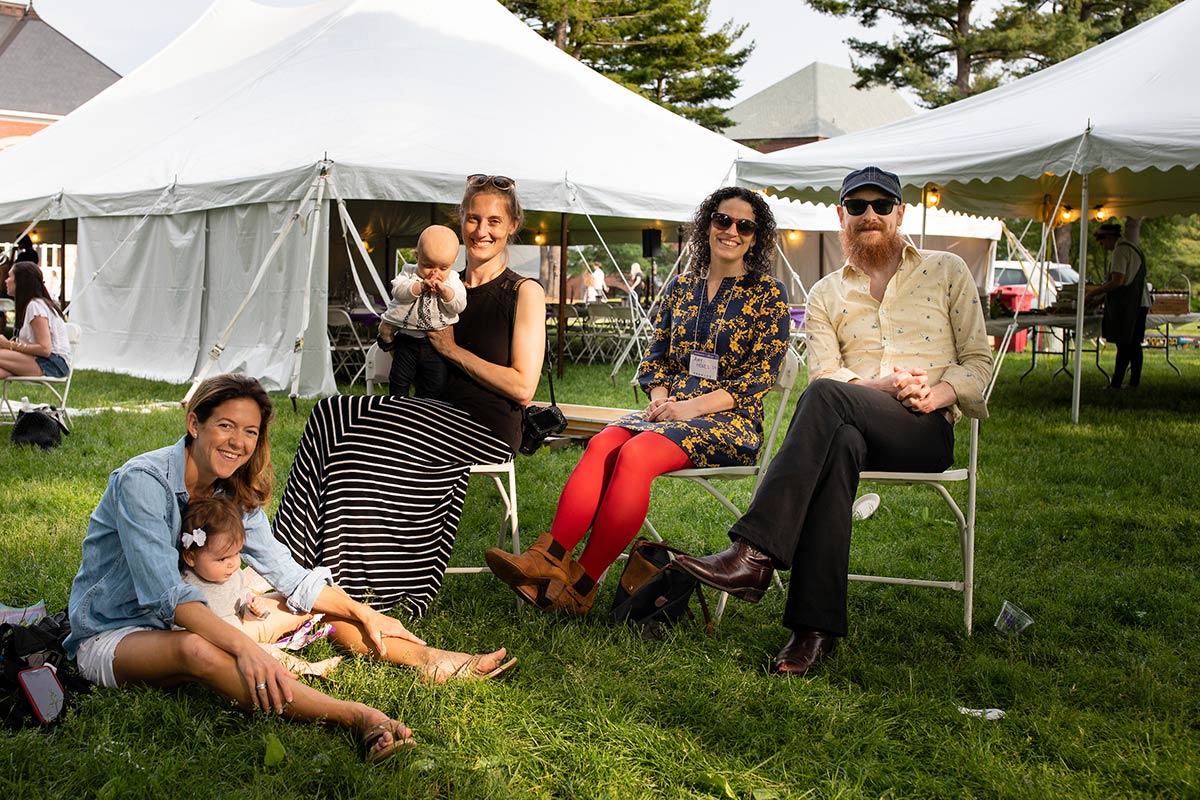 Four adults and two babies sitting just outside the luncheon tents during Reunion 2019