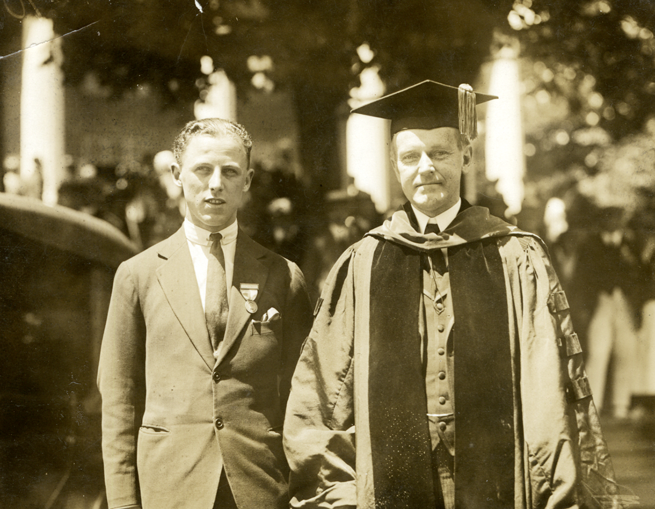 A sepia photo of two men in suits on the Amherst College quad