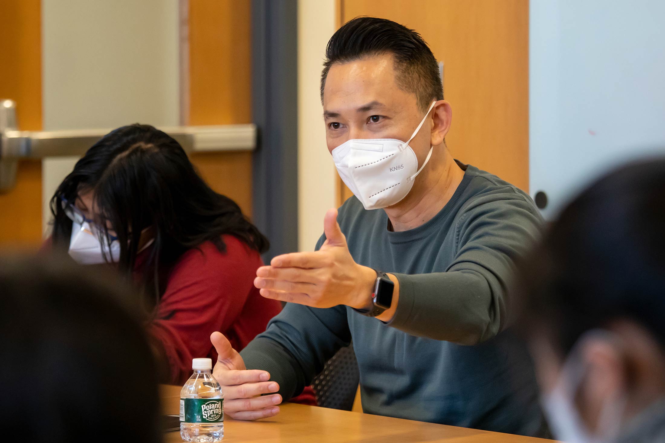 Viet Thanh Nguyen, wearing a kn95 mask, seated at a table, gestures while talking