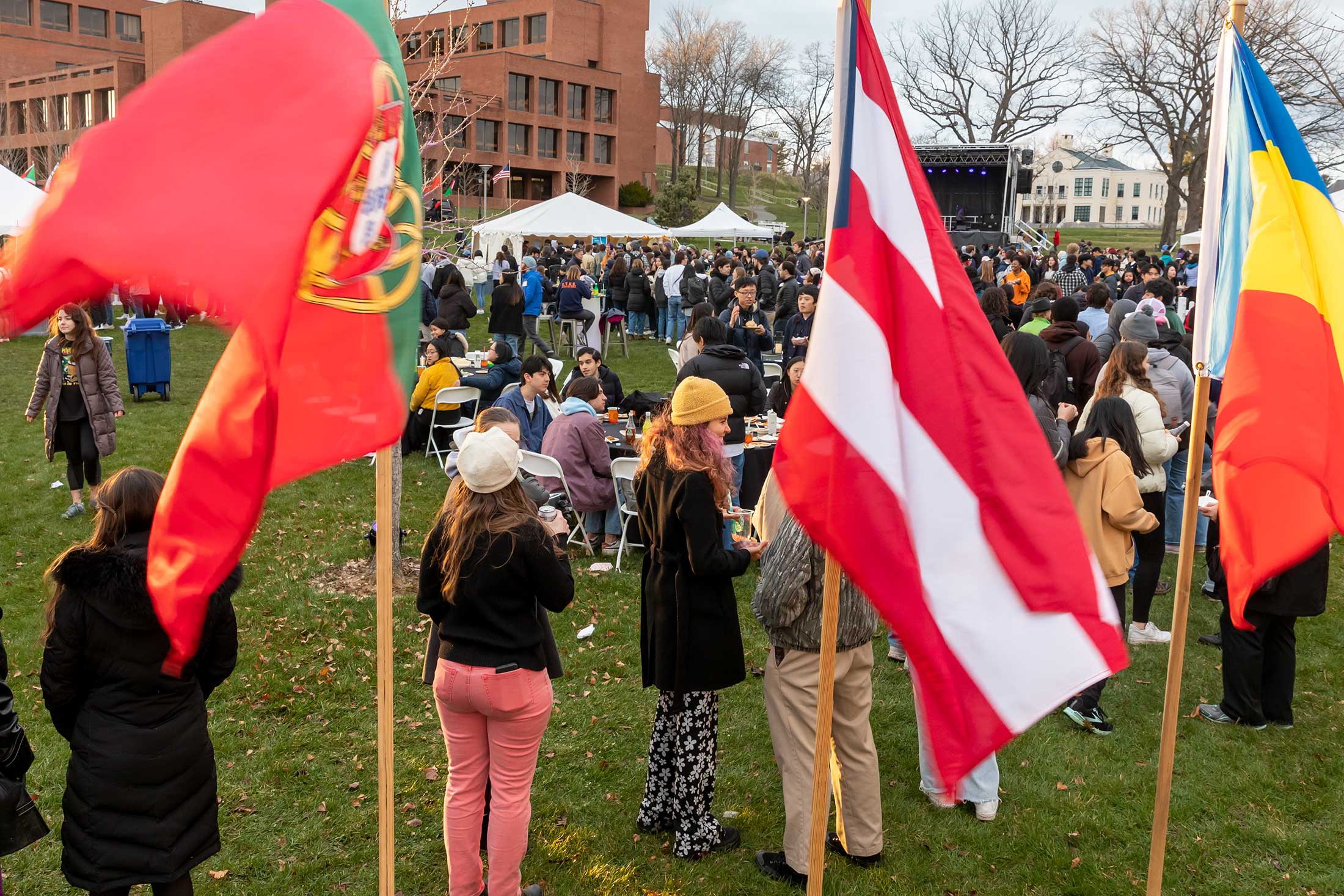 Students gather on the Amherst College campus. International flags are displayed in the forebround.