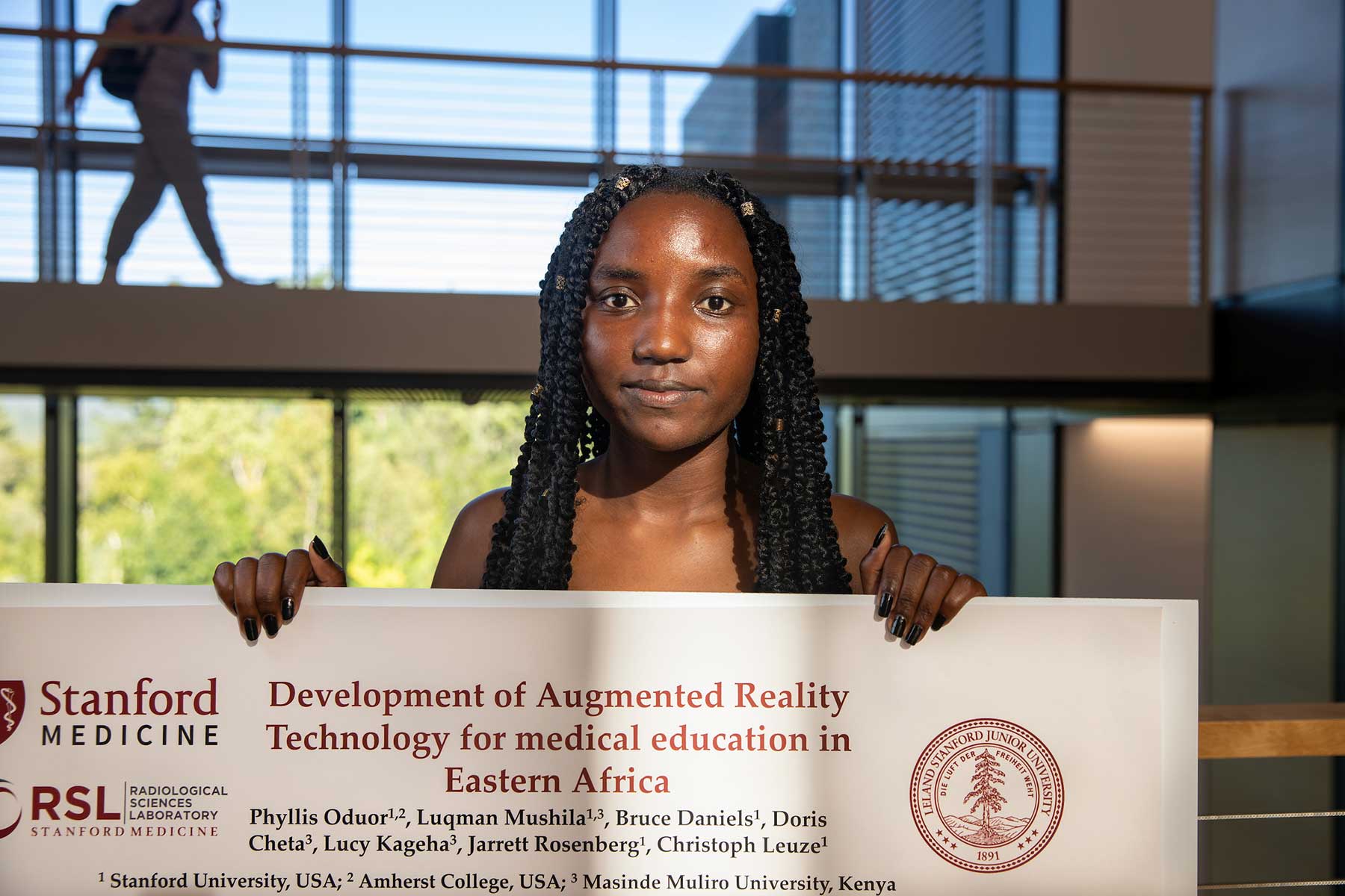 Phyliss Oduor '23 holds a poster about her research on Augmented Reality Technology for medical education in Eastern Africa.