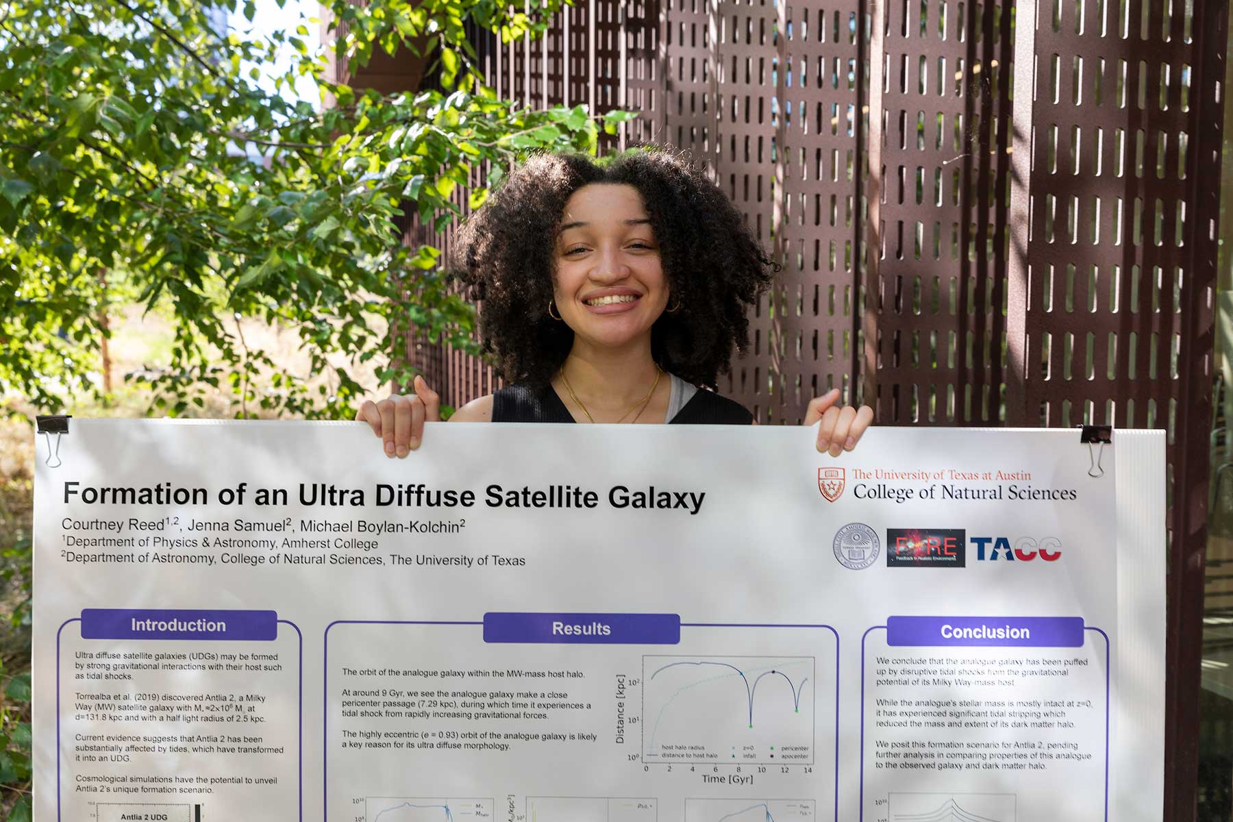 Courtney Reed '24 holds a poster on her summer research on Formation of an Ultra Diffuse Satellite Galaxy.