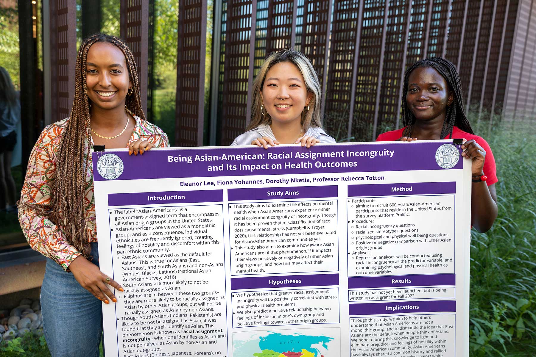 Eleanor Lee, Fiona Yohannes, and Dorothy Nketia hold a poster describing their summer research project.