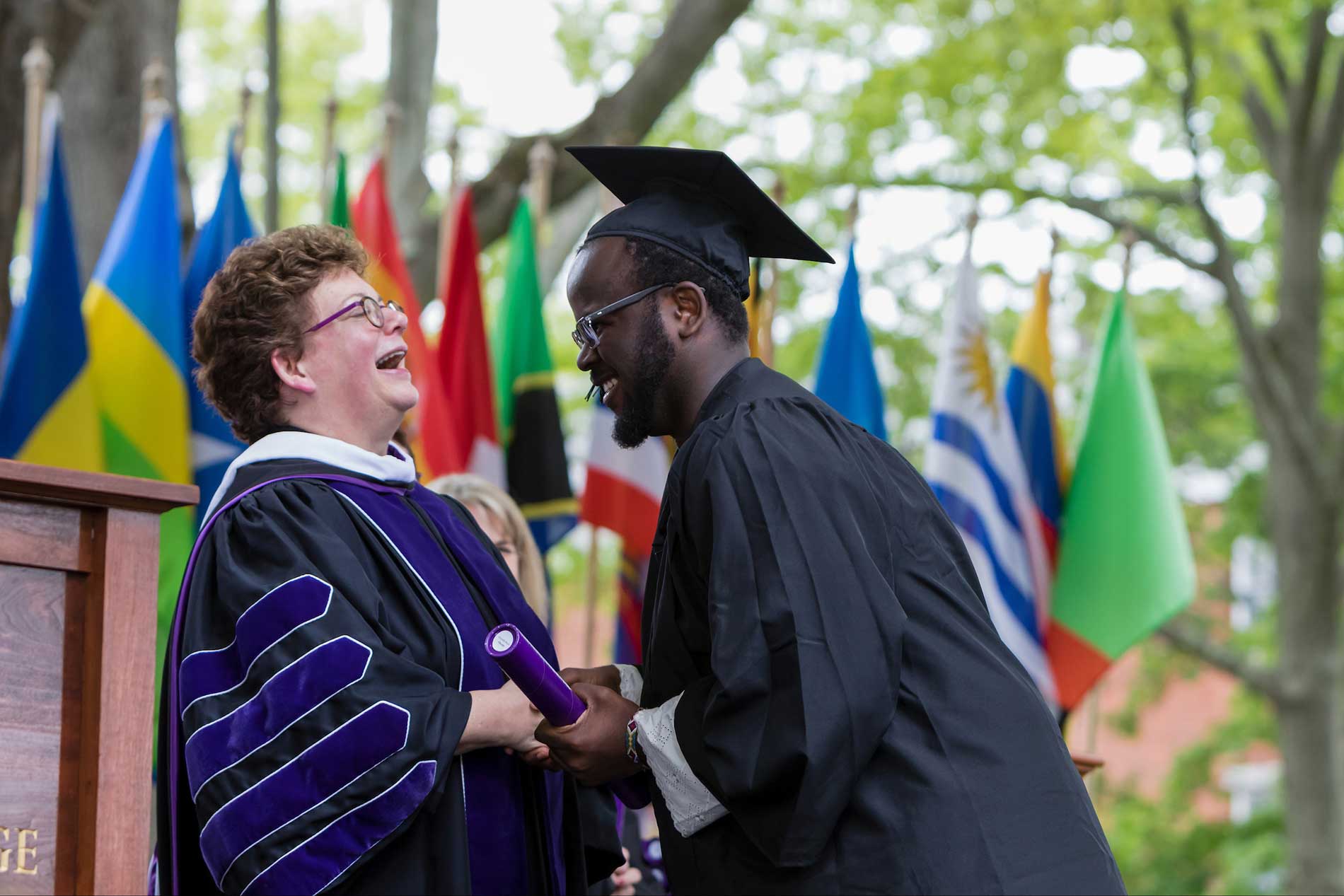 Biddy Martin shares a laugh a student as he receives his diploma during the 2016 commencement.