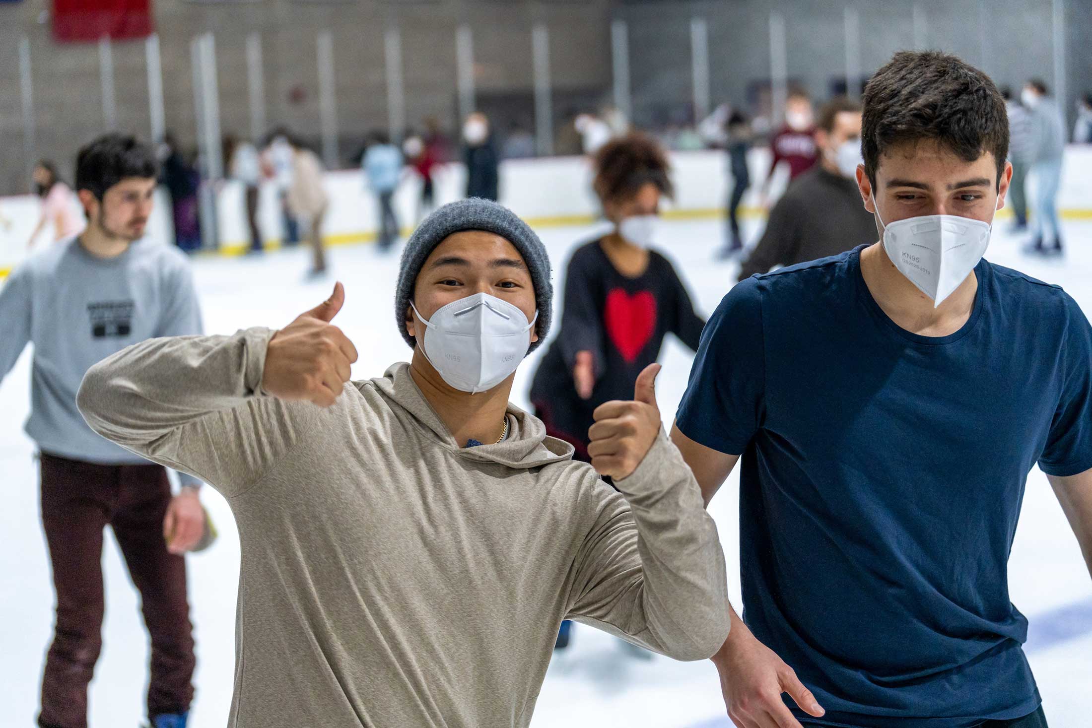 Several men ice skating, one giving a thumbs up gesture.