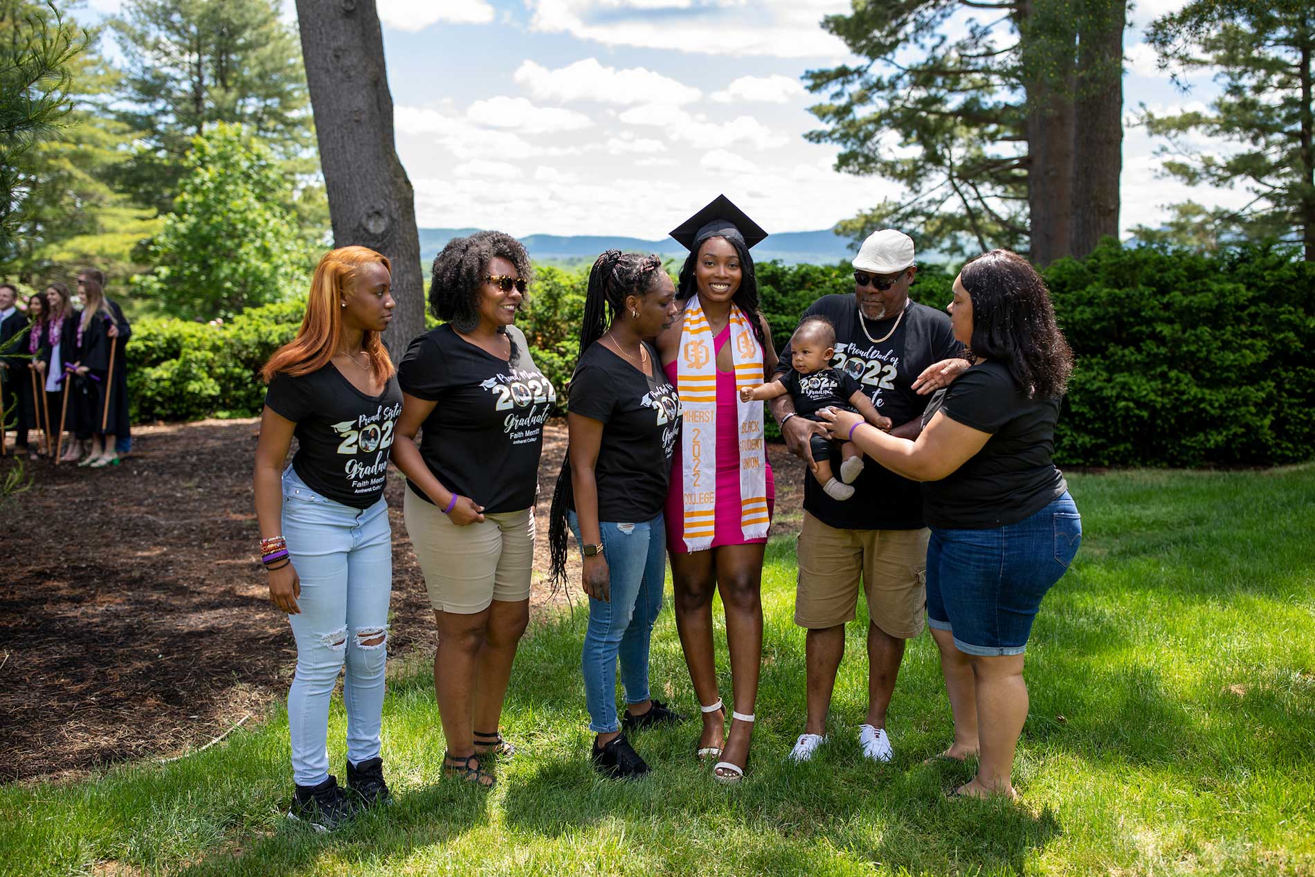 The family of a graduate gathers and poses for a photo infront of the Mt Holyoke range.