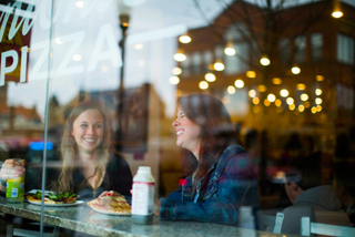students seen through a window talking in the local pizza place