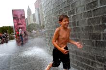 August 29, 2004<br><b>The Crown Fountain in Chicago’s Millennium Park</b><br>Of all the scenes that have played out since Millennium Park opened six weeks ago, this is the one that says the most: Children race around the black granite reflecting pool of the Crown Fountain, waiting for the giant human faces projected onto twin glass-block towers to spit jets of water. And they scream with delight when they get the shower.  That this inventive, multimedia spectacle takes place just a few blocks from stately old Buckingham Fountain offers a telling contrast. At Buckingham Fountain, all you can do is stand by and watch water shooting out of sea creatures' mouths. But at the Crown Fountain, the atmosphere is raucous, festive and, above all, interactive. It's the difference between architecture as object and architecture as event -- and it is among the reasons that Millennium Park has instantly established itself as a triumphant, if still-imperfect, public space.<br><i>Chicago Tribune photo by Kuni Takahashi</i>