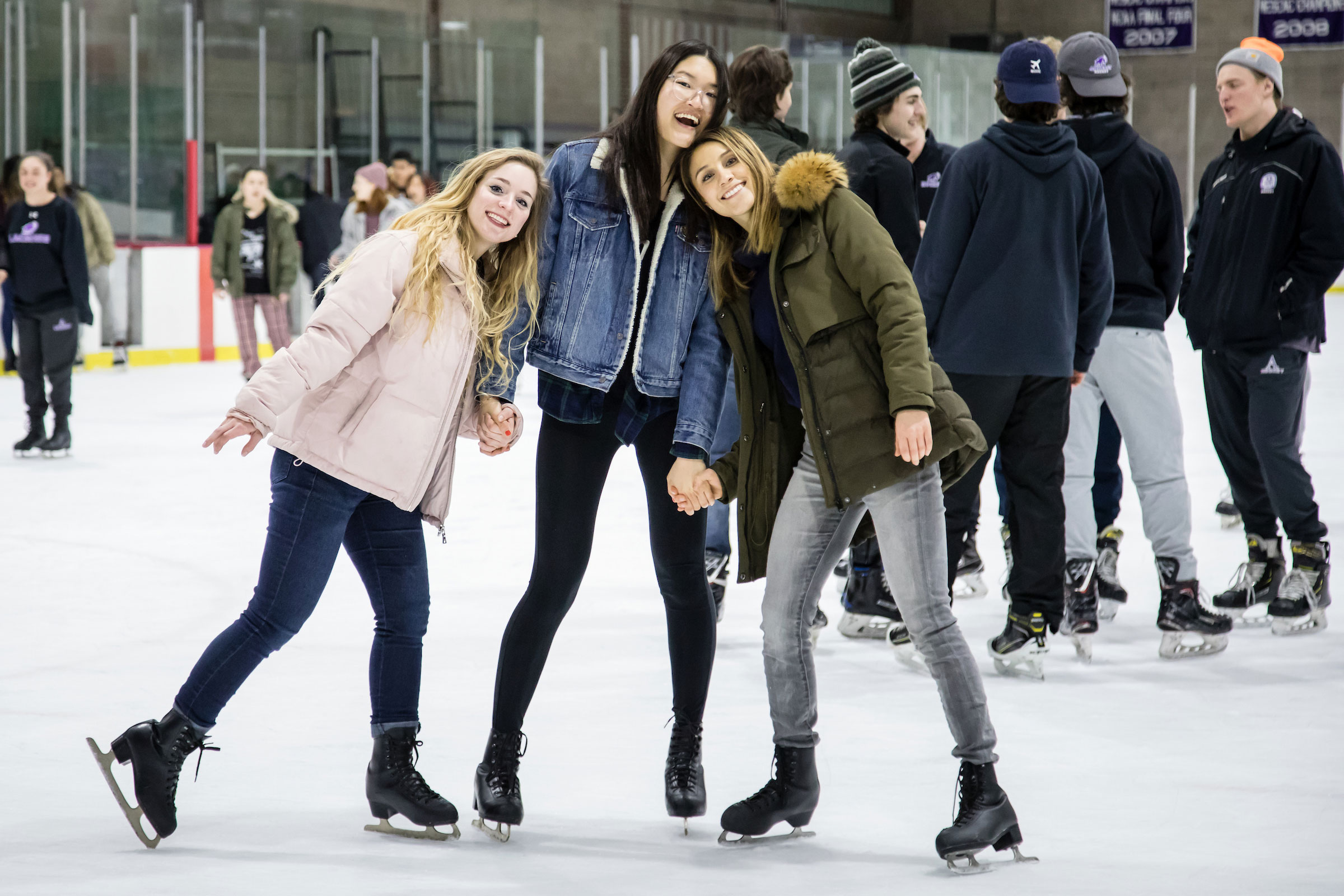 Three women pose together on the ice skating rink