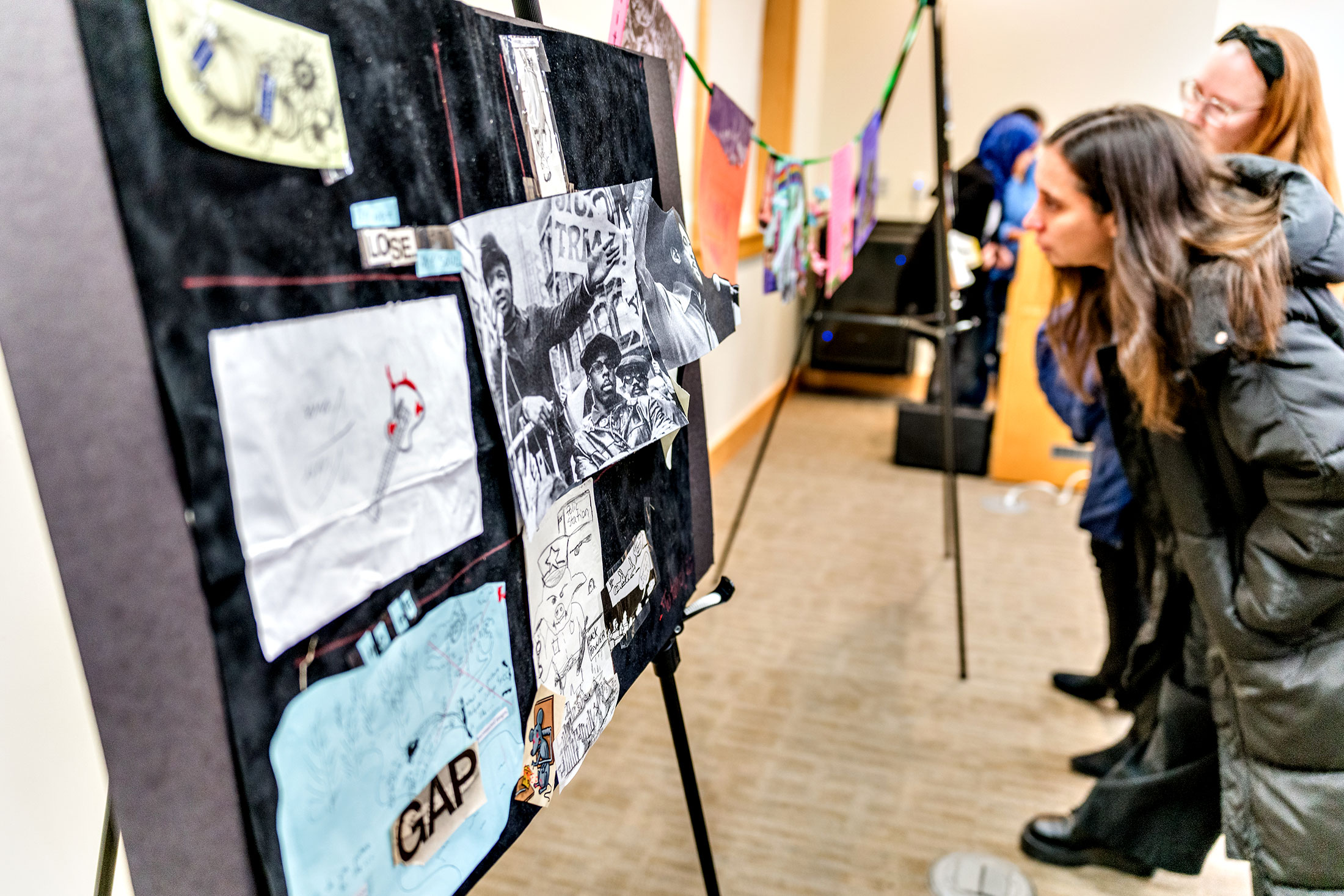 A woman inspects a wall of artwrok.