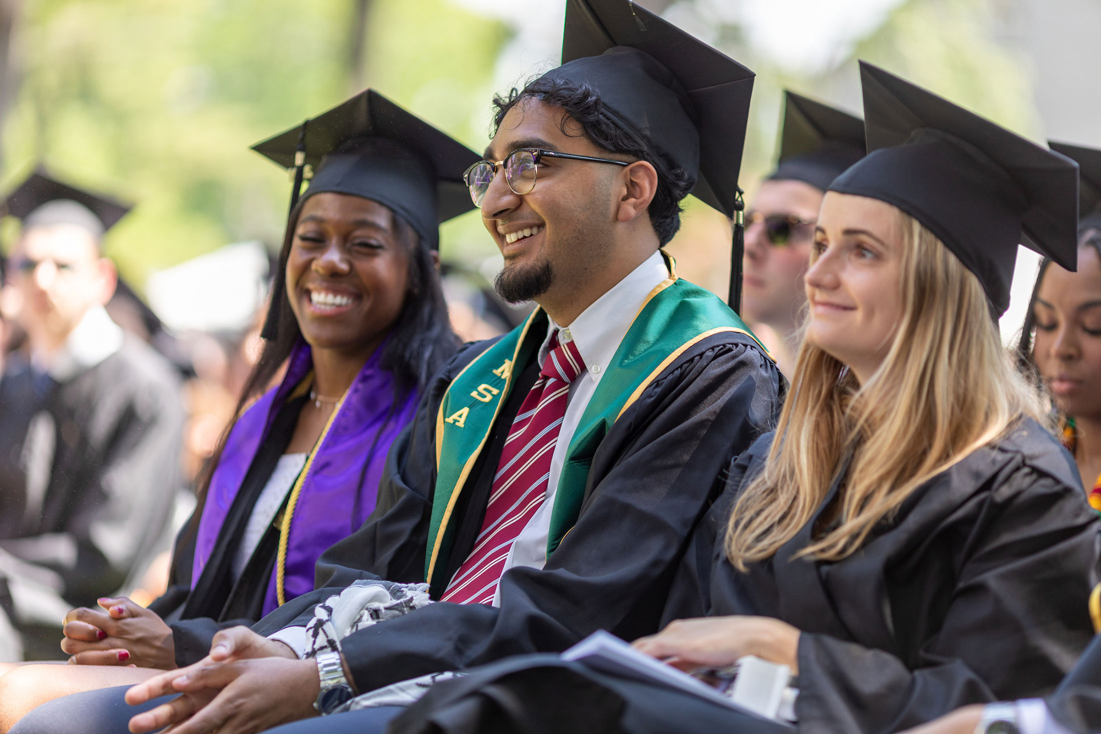Three graduating seniors listen during the Commencement ceremony at Amherst College..