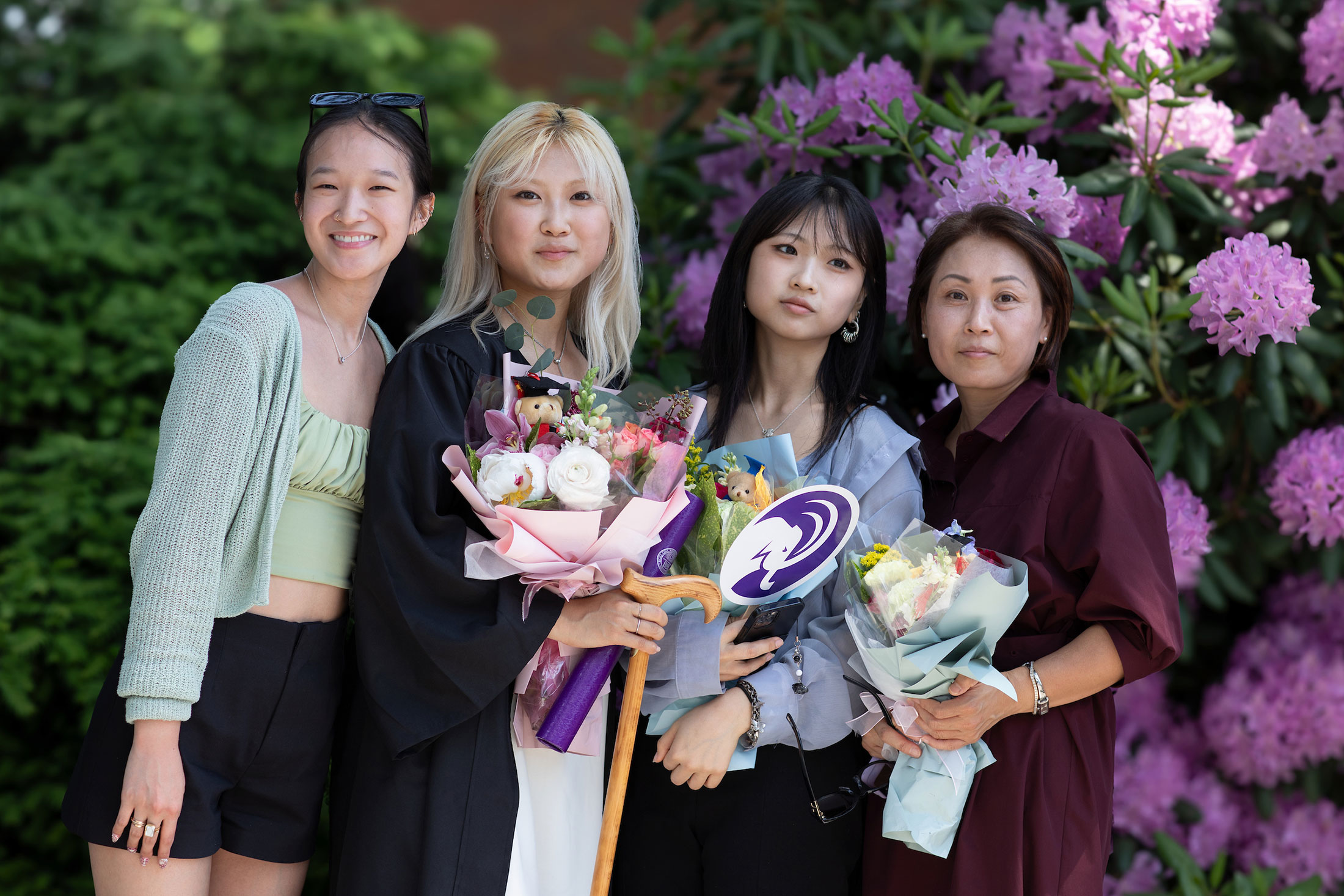 A graduate holding flowers poses with her family.
