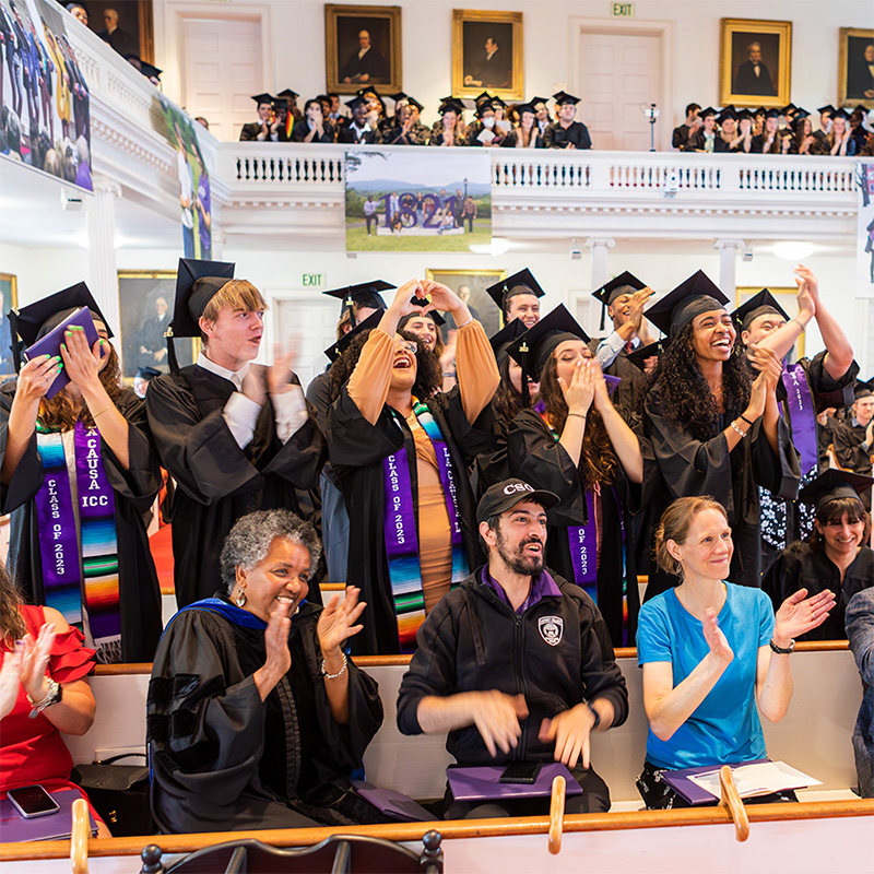 People cheering in Johnson Chapel wearing Commencement regalia