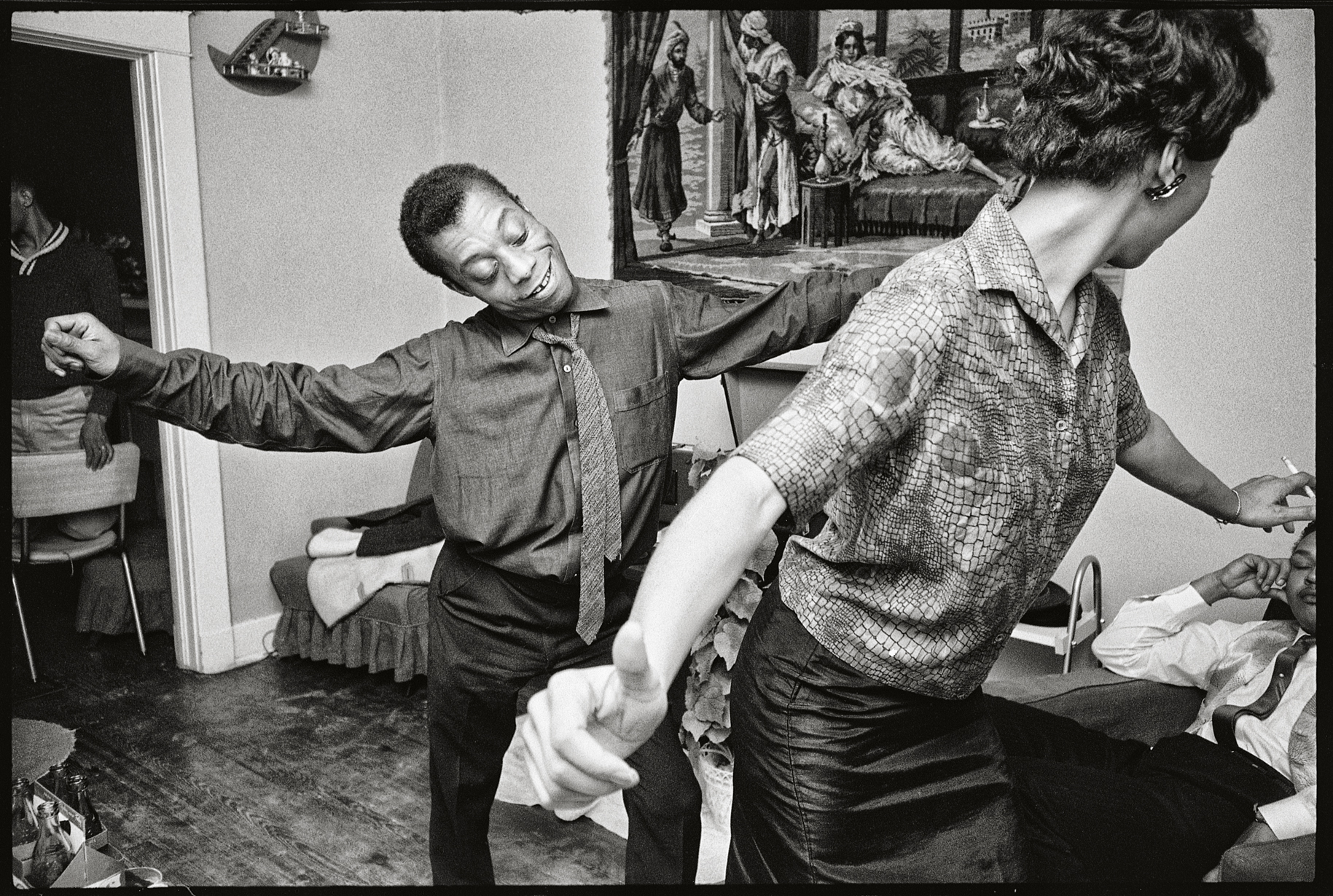 Black and white photograph of James Baldwin dancing the “hitchhike” with a CORE worker.