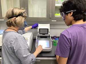 A teacher and student working on a piece of lab equipment