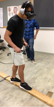Image of student wearing virtual reality headset and walking on a wooden board on the floor