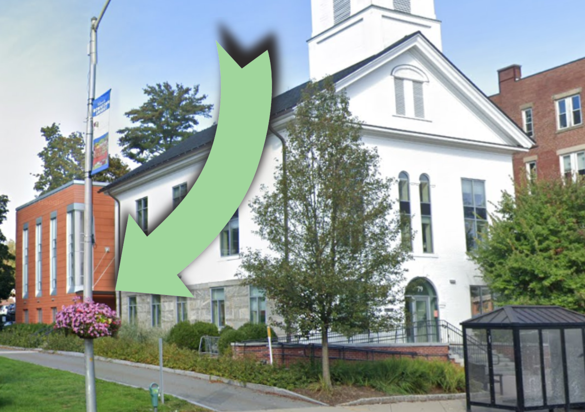 A large white building that looks like a church with a large green arrow pointing to the side of the building