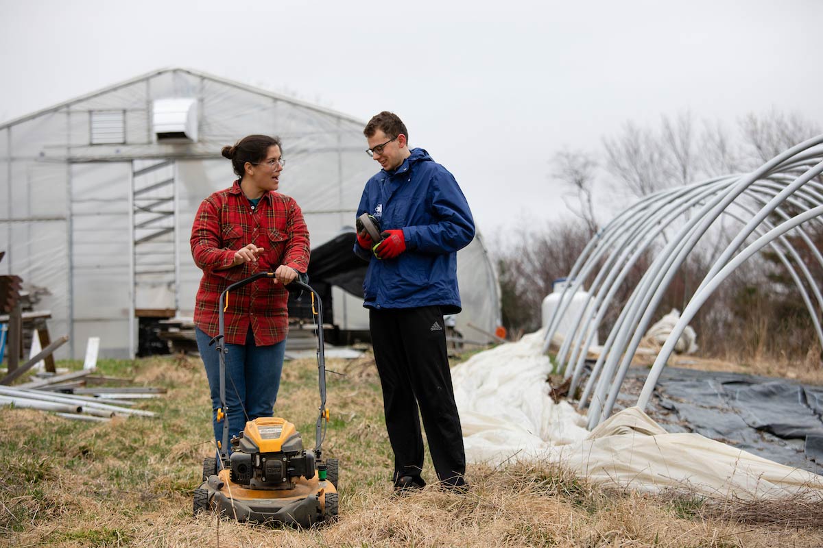 Maida Ives teaches a student farmer how to start the mower