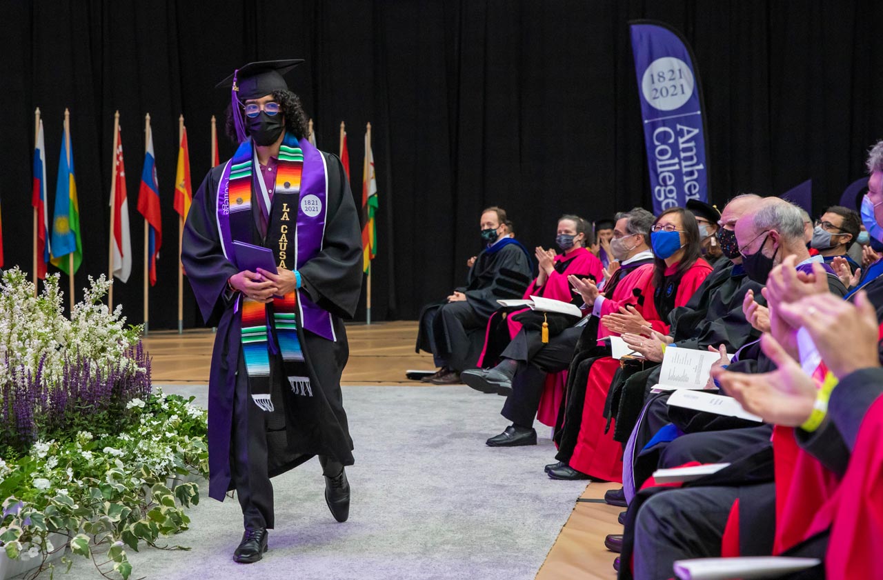 a graduating senior walks past applauding faculty