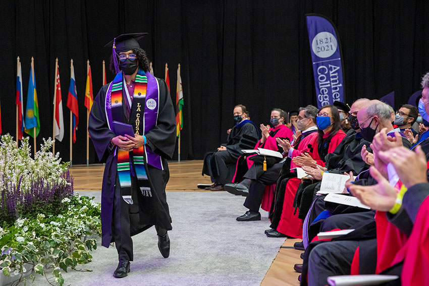 A student in commencement regalia leaving the stage after receiving his diploma.