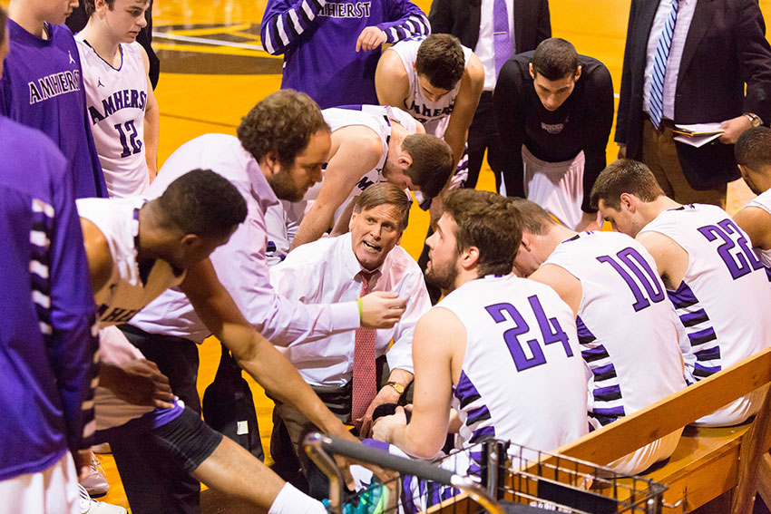 Coach Dave Hixon in a huddle with members of the men's basketball team