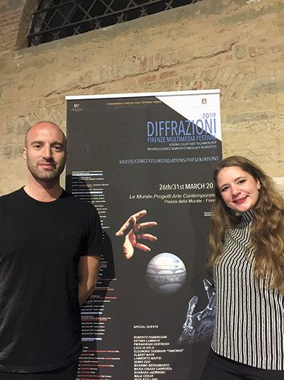 A man and woman standing in front of a poster saying Diffrazioni