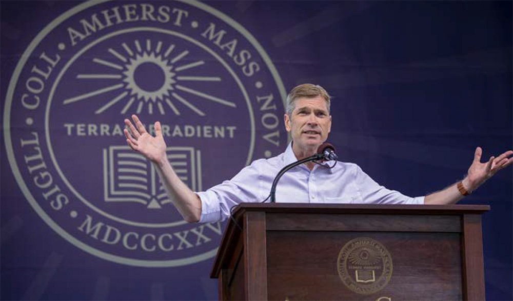 Michael Elliott speaking at a podium with an Amherst Seal as a backgrond