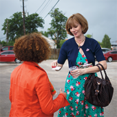A woman handing a card to a woman in an orange jacket