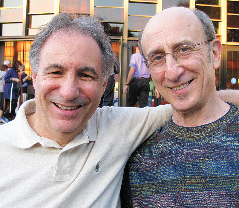 Two men smiling at the camera outdoors