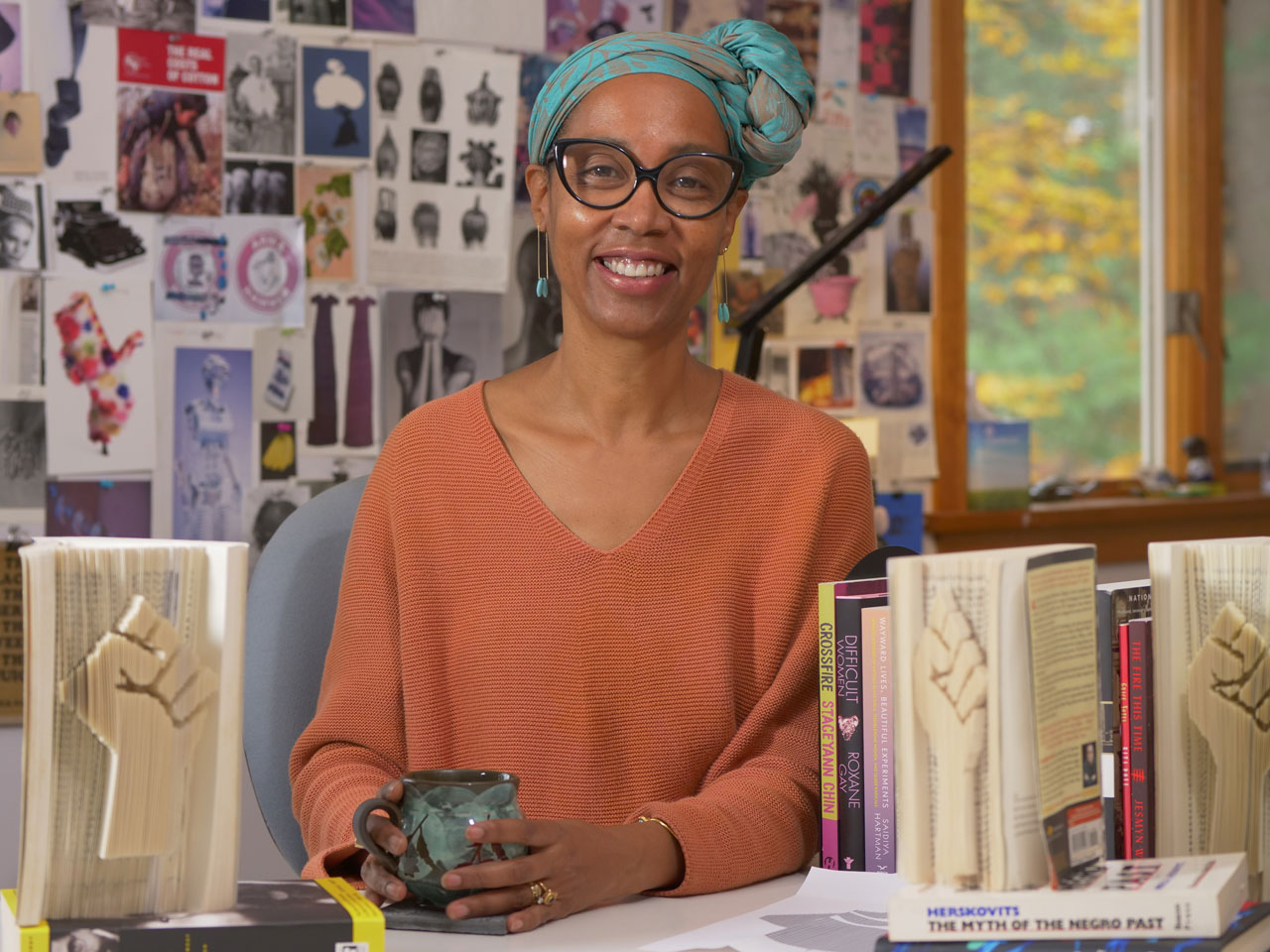 Sonya Clark sits in her art studio with sculpted books next to her